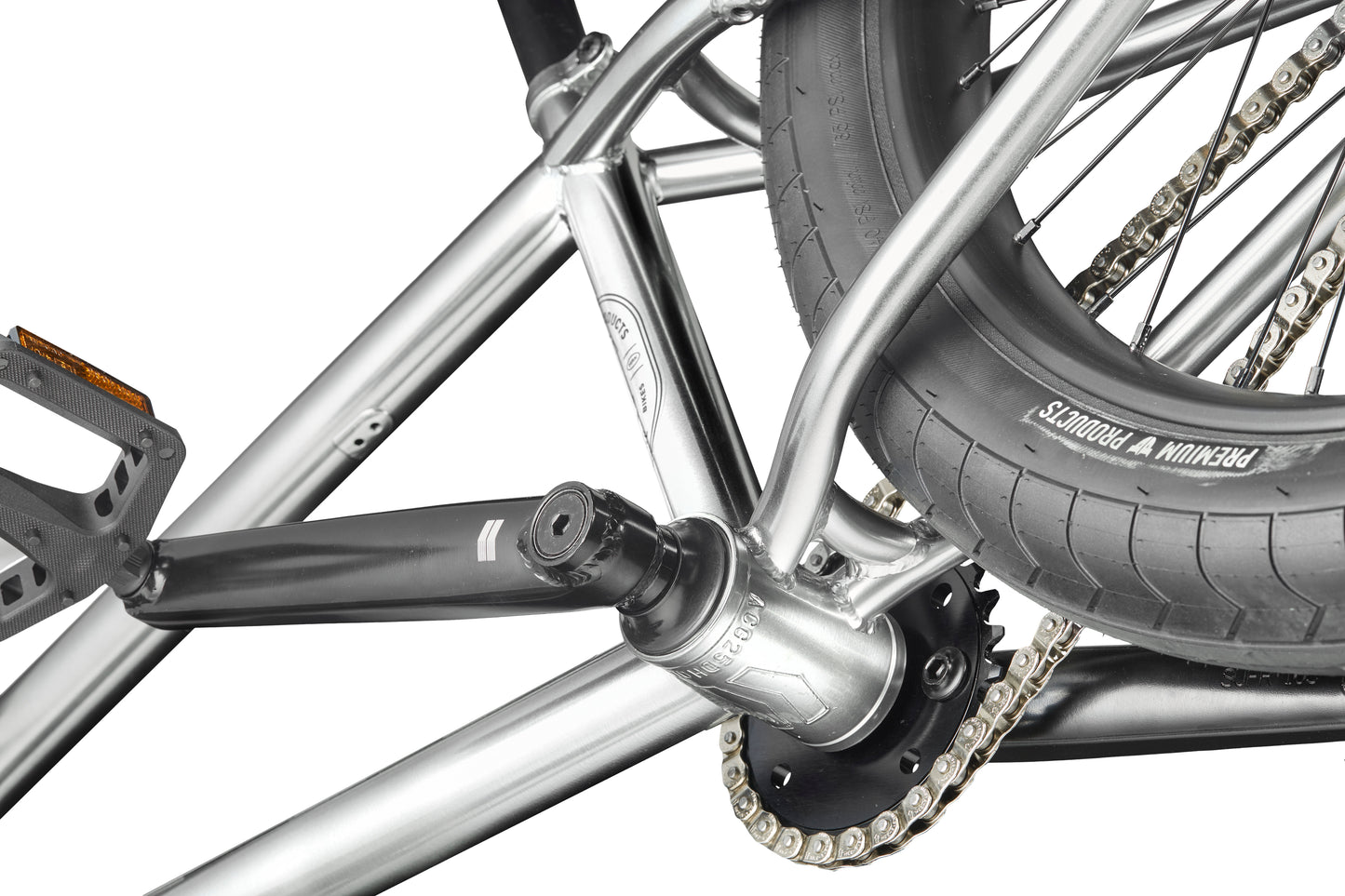 Close-up of a Hoover BMX bike’s rear wheel, chain, pedal, and silver frame, focusing on the crank and tire tread.