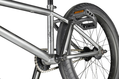 Close-up of a Hoover bike’s rear wheel, pedal, chain, and metal frame on a white background.