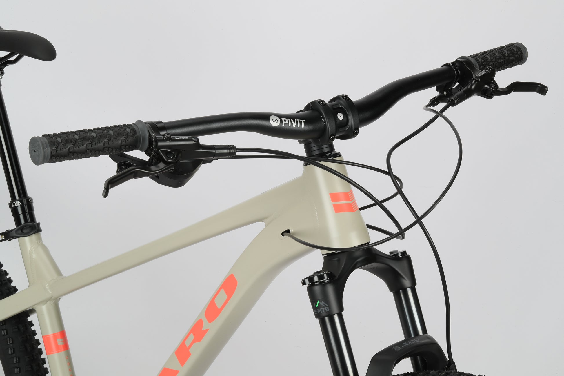 Close-up of Double Peak 1s beige handlebars with Rock Shox Judy fork, PIVOT branding, and black grips on a white background.