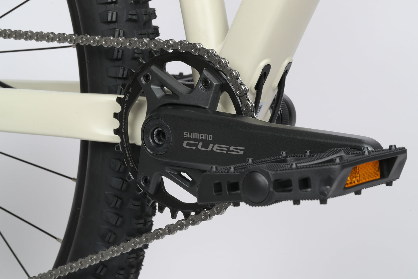 Close-up of Shimano Cues drivetrain with crankset/pedal, showing part of Double Peak 1 tire and chain.