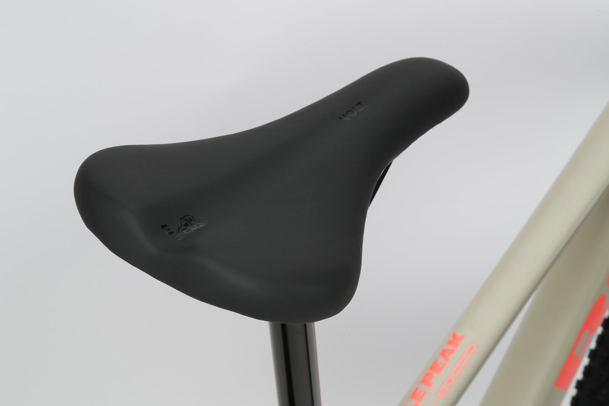 Close-up of a sleek black bicycle seat on a gray Double Peak 1 frame with partial red-orange text visible.