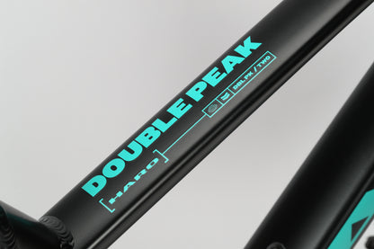 Close-up of a black aluminum frame with turquoise DOUBLE PEAK 2 text and social media icons on a light gray background.