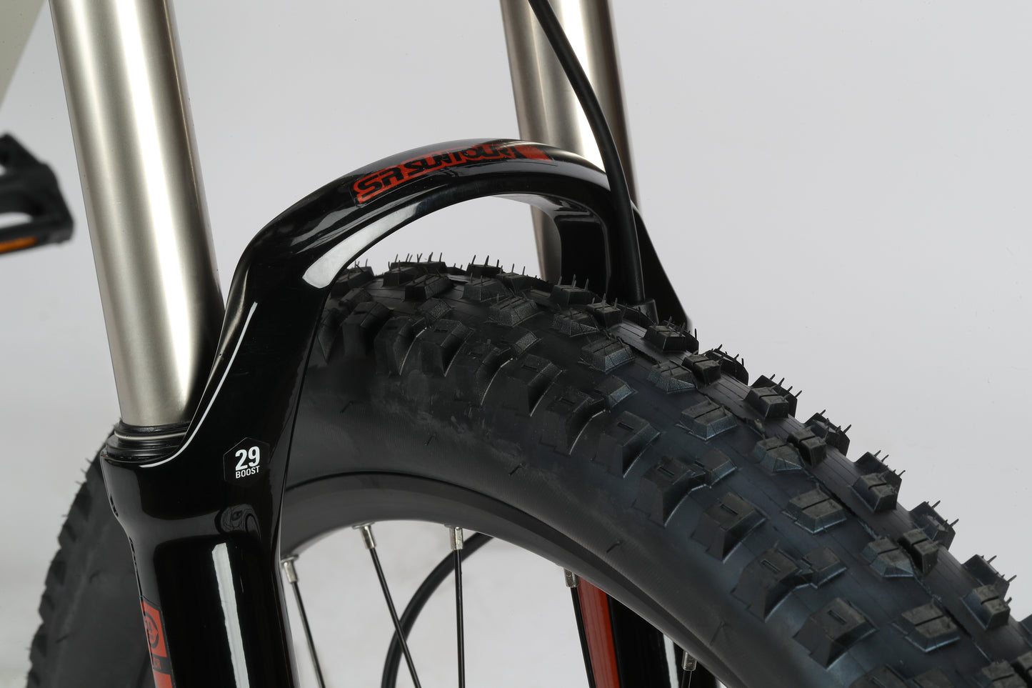 Close-up of a SunTour suspension fork with large 29 tire on the Double Peak 2s sleek aluminum frame.