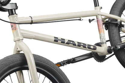 Close-up of a beige BLVD BMX frame, featuring the logo, tires, pedals—highlighting its all-around performance.