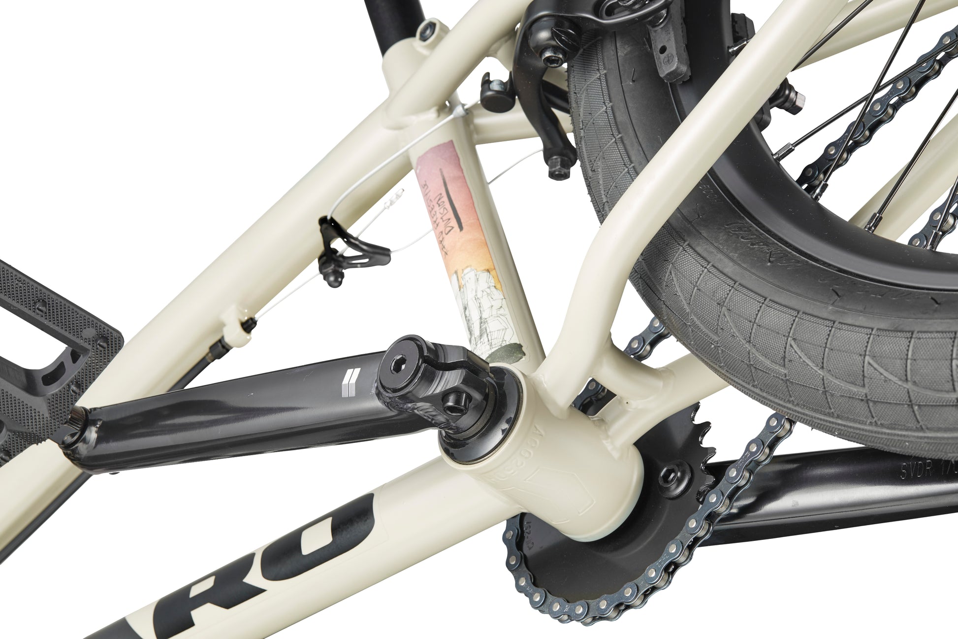 Close-up of a beige Haro BLVD bike frame, crankset, rear wheel, and a small multicolored sticker on the seat tube.