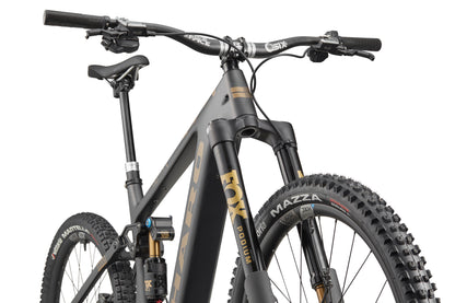 Low-angle shot of the eGreer Carbon Top Shelf: a modern ebike with thick tires, front suspension, and matte black-gold accents.