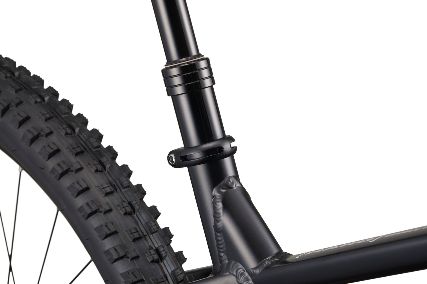 Close-up of Double Peak bike’s seat post clamp, rear tire, and frame with visible welds.