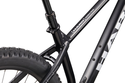 Close-up of Double Peak mountain bike’s black frame, seat tube, rear tire, logos, and hydraulic disk brakes.