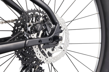 Close-up of Double Peak’s rear wheel, showcasing hydraulic disc brakes, sprockets, and spokes against a white background.