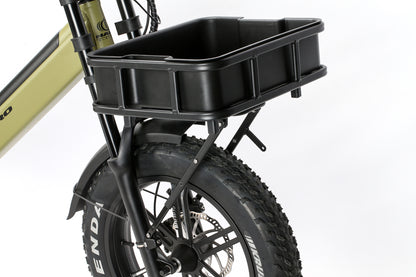 A close-up shows a cargo-style front rack on a bike with wide tires and disc brakes, featuring the black, box-shaped Atran Velo Bakery Crate mounted on an olive green frame.