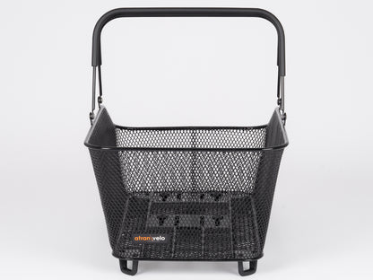 The Atran Velo Daily Basket Large is a black metal mesh bike basket with a sturdy handle, featuring the logo on the front. It has a rectangular shape, solid base, and small support feet, easily integrating with the AVS system for secure mounting.