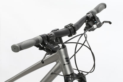 The image showcases the Bridgeport ST MicroShift by Haro MTB, highlighting its grip handles, brake levers, and gear shifters. Cables are neatly routed along a metallic gray frame, emphasizing the bicycles front-end functionality and design.