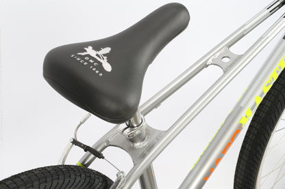 Close-up of the DMC 24 bicycle seat on a silver frame, featuring the SINCE 1908 design. This Haro Bikes model has BMX-style vibrant yellow and orange accents, textured black tires, and sleek Freestyler bars enhancing its dynamic appearance.