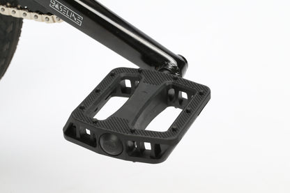 Close-up of a black pedal attached to a metal crank arm on the Haro Bikes Dana chromoly frame. The pedal features a textured surface for grip and is mounted on the bikes responsive geometry against a plain white background.