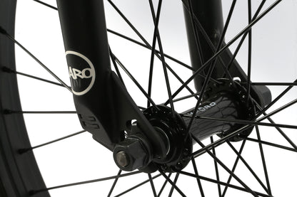 Close-up of the Leucadias black front wheel by Haro Bikes, focusing on the fork and spokes. The Haro logo is visible on both the fork and hub, highlighting the bikes intricate design and engineering reminiscent of a skateboards sleek lines.