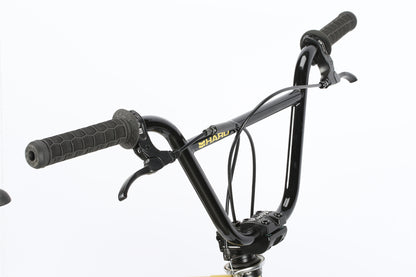 Close-up of Leucadia DLX black handlebars by Haro Bikes, showcasing textured grips, brake levers, and a gyro detangler for smooth spins. Mounted on a freestyle BMX frame with visible cables against a plain white background.