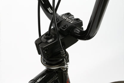 A close-up shows the black handlebar stem of a Leucadia DLX from Haro Bikes, complete with branding, connected to the fork. Ideal for freestyle BMX, it includes several black cables and a Gyro detangler, all set against a white background.