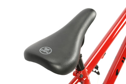 Close-up of the Leucadia DLX from Haro Bikes, featuring a black seat with logo on a bright red frame. This stylish freestyle BMX bike boasts chromoly cranks for top-notch performance and durability, set against a crisp white background that highlights its vibrant colors and sleek design.