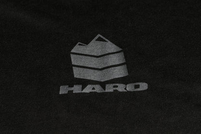 The Haro MTB DryBlend Long Sleeve Shirt from Haro Bikes features a dark fabric with a gray geometric mountain logo, HARO in bold letters, and offers moisture-wicking properties and a classic fit for comfort.