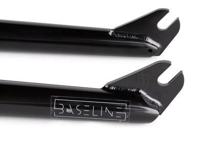 Close-up of two black metal Baseline Forks by Haro Bikes, featuring precision welds and cutouts. Made from durable chromoly, the lower fork displays BASELINE in a stylized font.